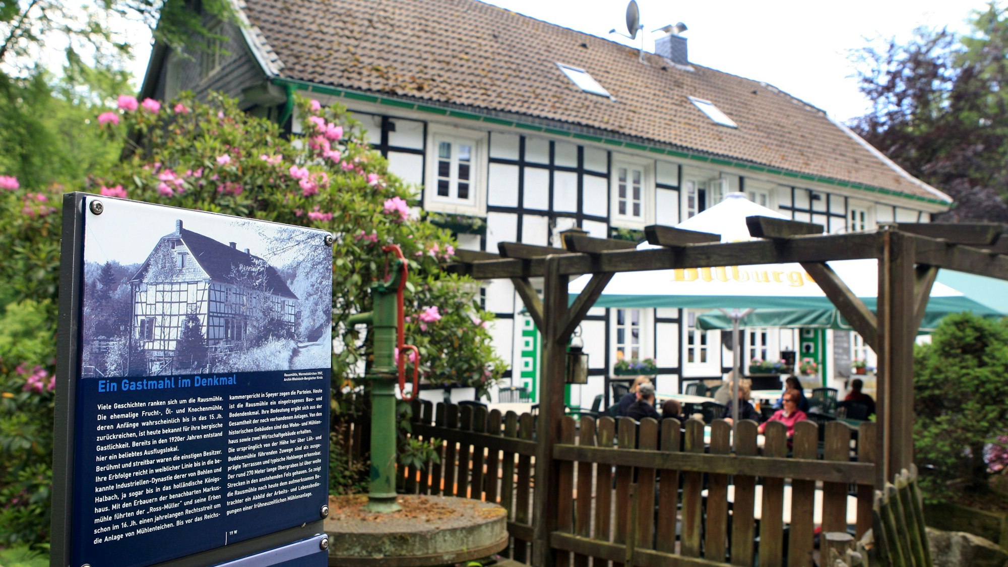 Eine Infotafel des Eifgenbachwegs steht vor dem Gebäude der Rausmühle.