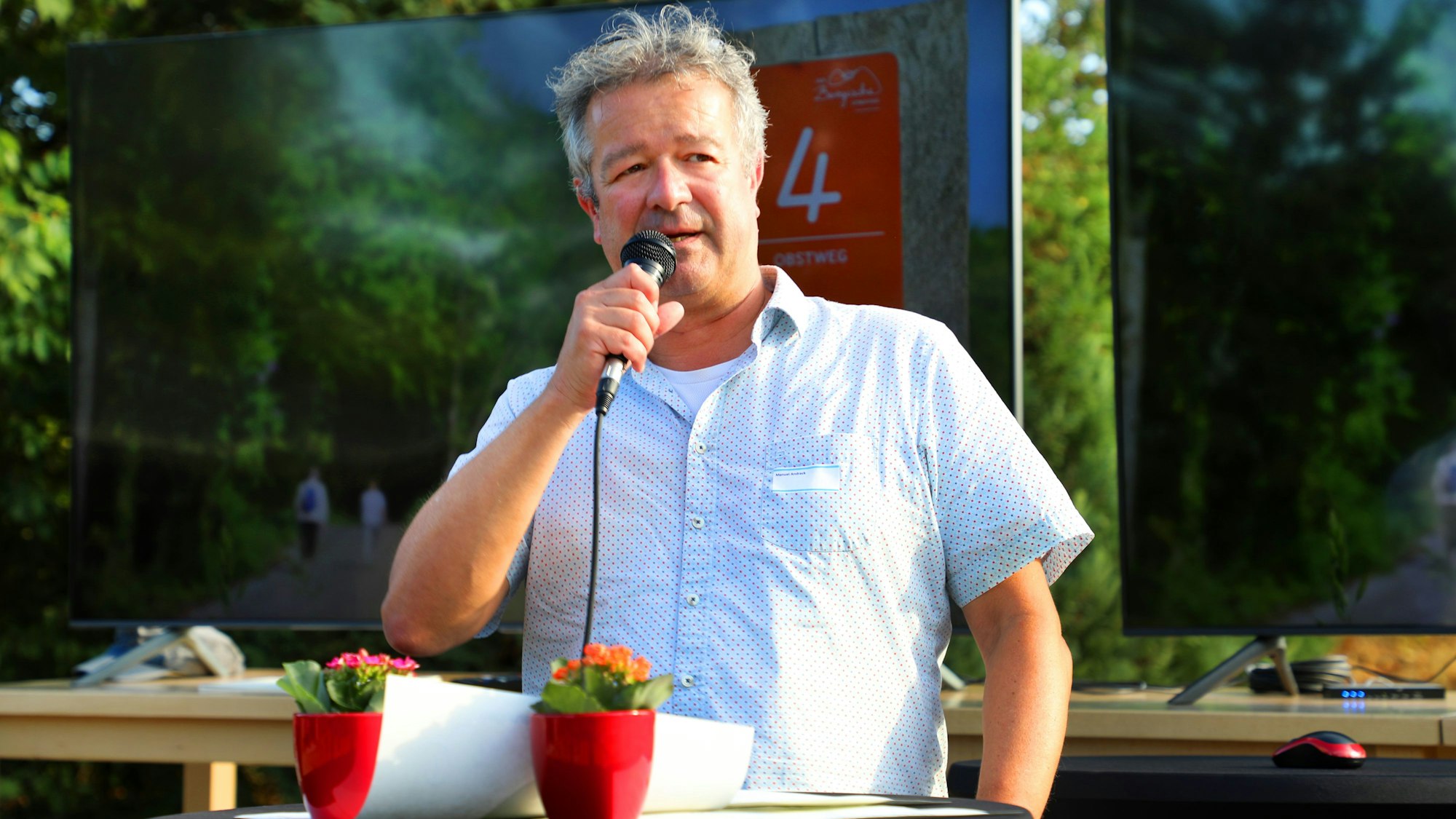 Manuel Andrack steht mit einem Mikro auf einer Bühne beim Bergischen Tourismustag anlässlich des zehnjährigen Bestehens des Bergischen Wanderlands.
