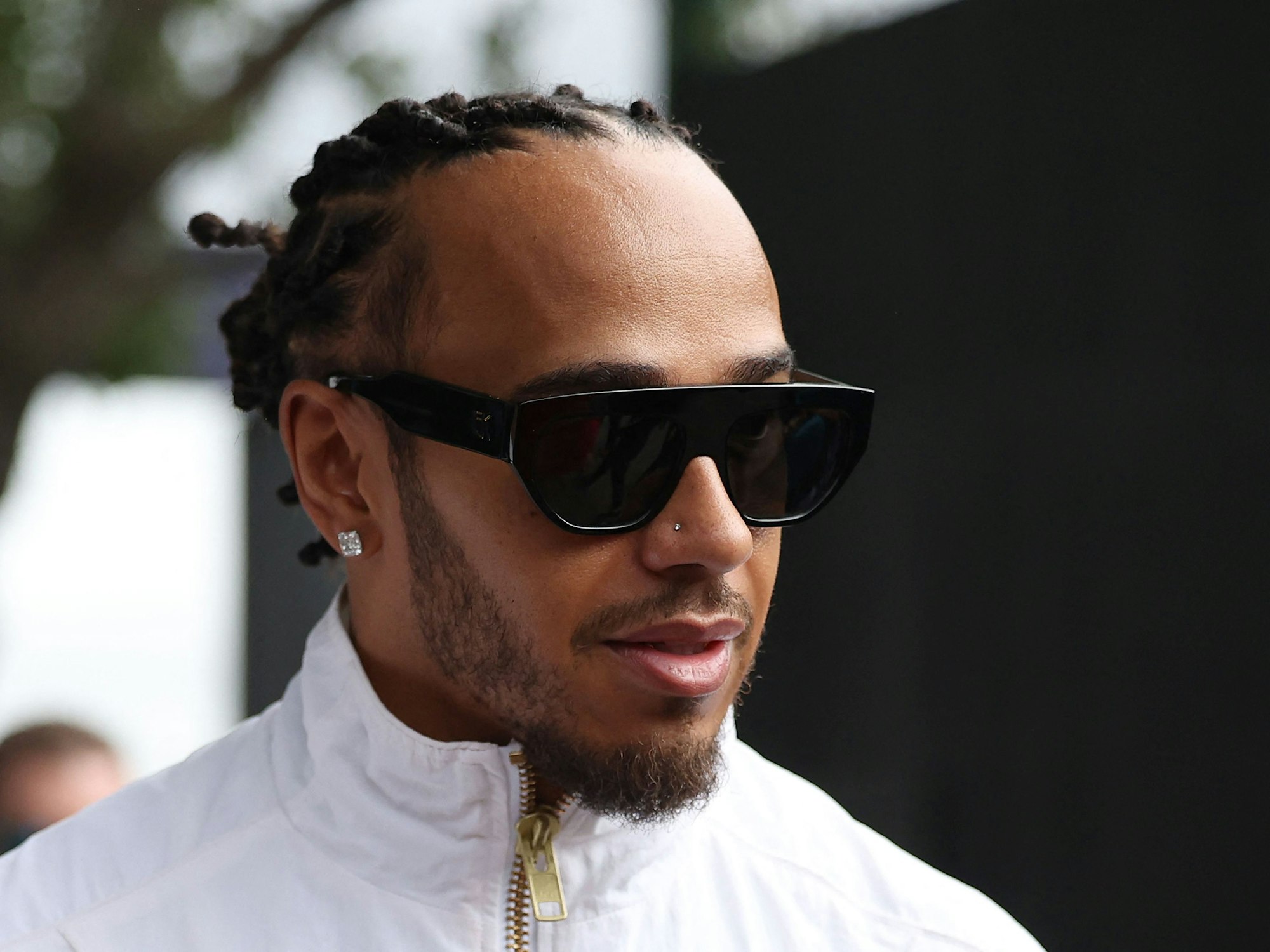 Lewis Hamilton kommt mit Sonnenbrille ins Fahrerlager.