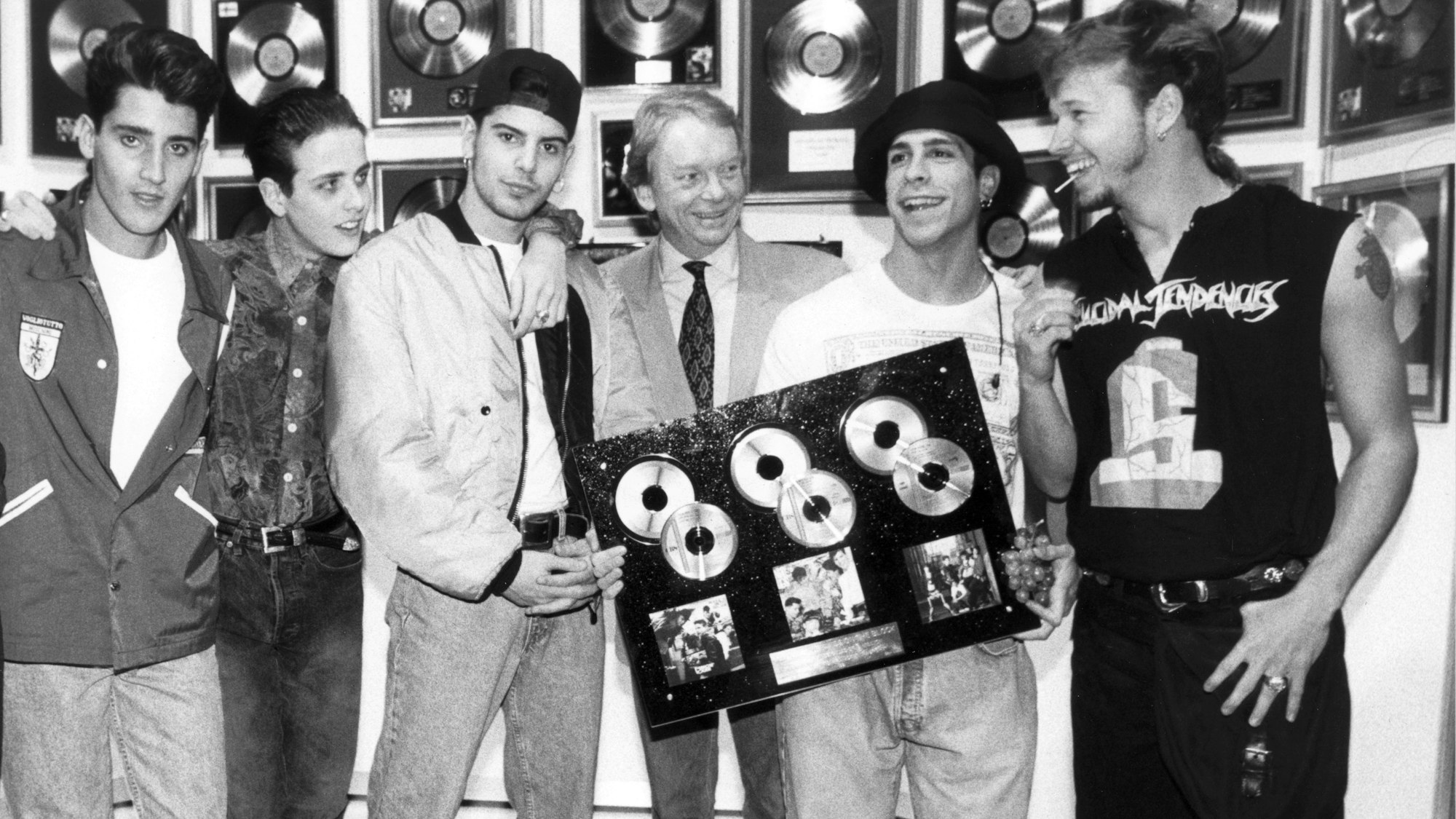 Die Band „New Kids on the Block“ hält mehrere Goldene CD's in der Hand und posiert für die Kamera.