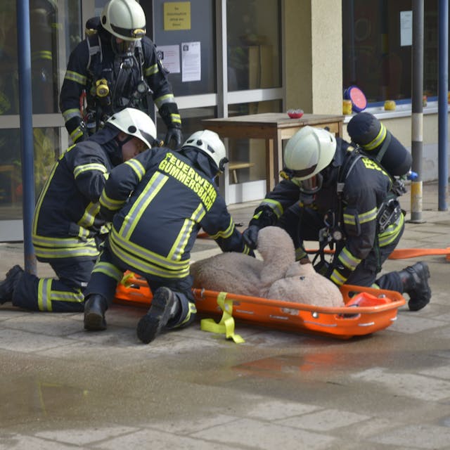 Bei der Feuerwehrübung an der AWO-Kindertagesstätte Lina-Ege wird der Teddy „gerettet". Die Feuerwehrleute haben ihn auf eine Trage gelegt.