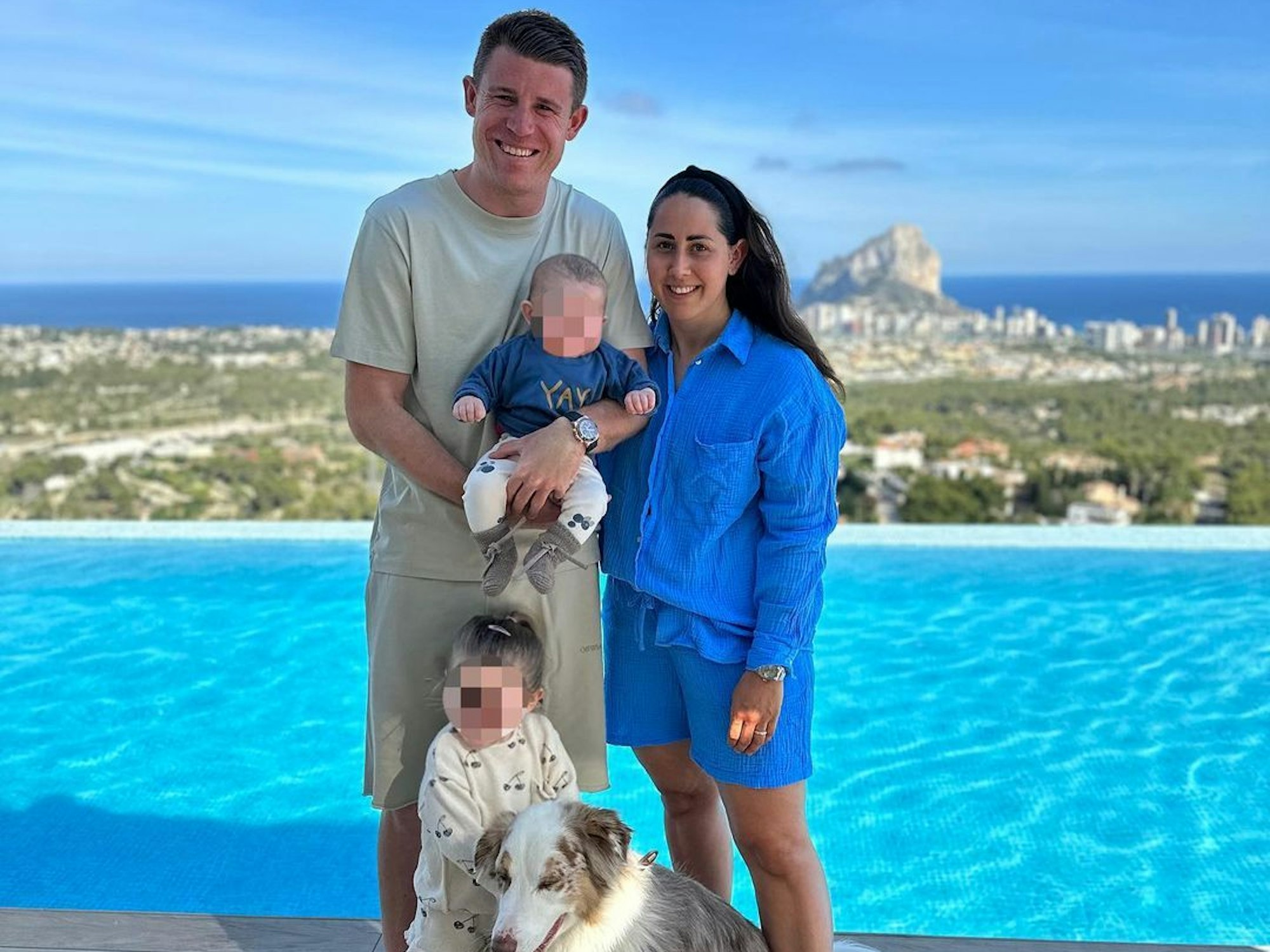 Dominique Heintz mit seiner Frau Laura, seinen beiden Kindern und seinem Hund im Spanien-Urlaub. Die Familie steht vor einem Pool mit Blick aufs Meer.