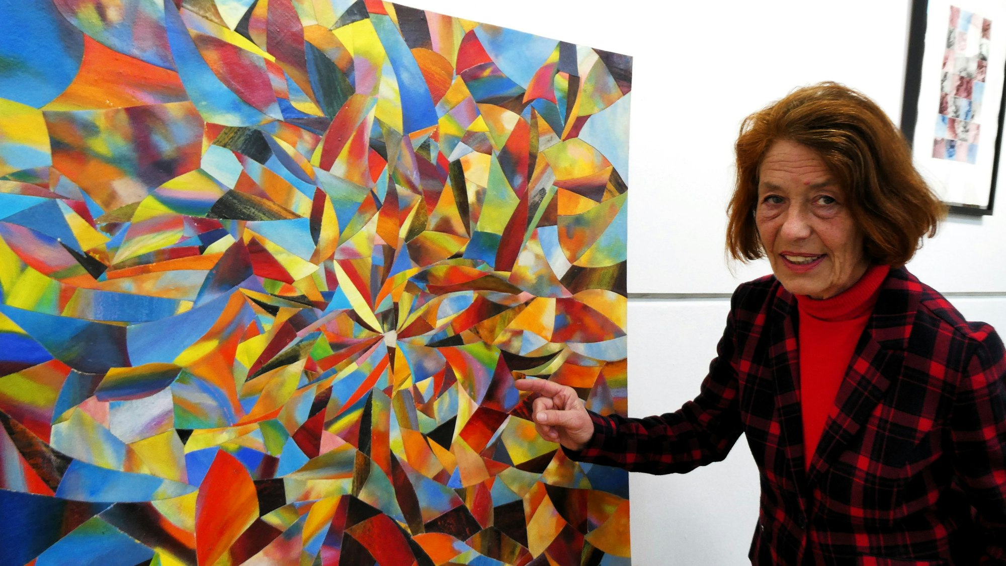 Eine Frau steht neben einem Bild, auf dem die Farben geradezu explodieren.
