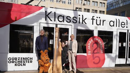 Stefan Englert, Geschäftsführender Direktor des Gürzenich Orchester (l.), und Stefanie Haaks, Vorstandsvorsitzende der KVB, präsentieren mit einem Musiker die Bahn.