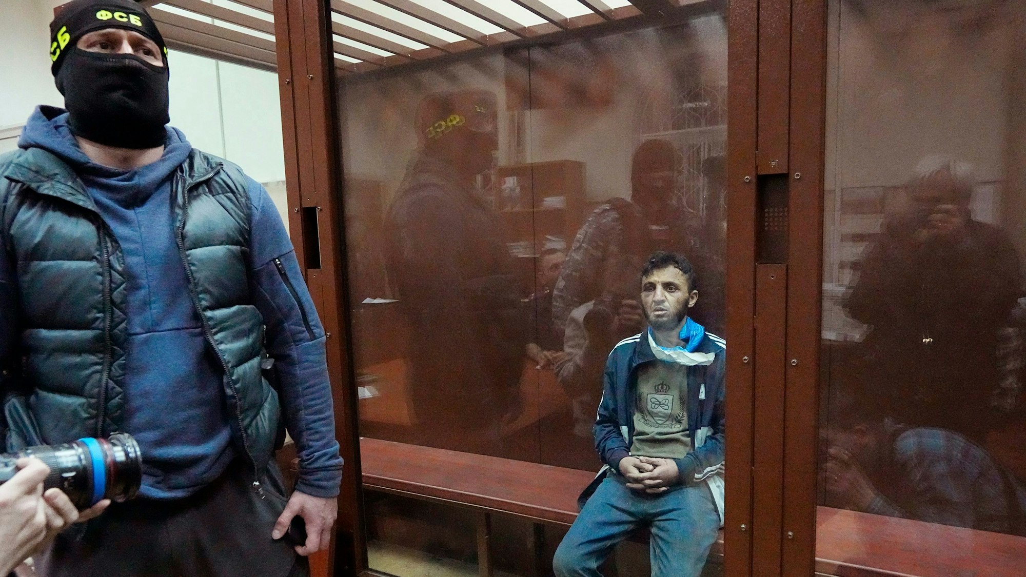 Moskau: Ein Tatverdächtiger des Terroranschlags auf die Konzerthalle Crocus City Hall sitzt in einem Glaskäfig im Bezirksgericht Basmanny. Auf der Mütze des Sicherheitsmanns steht auf kyrillisch FSB, die Abkürzung für den russischen Inlandsgeheimdienst.