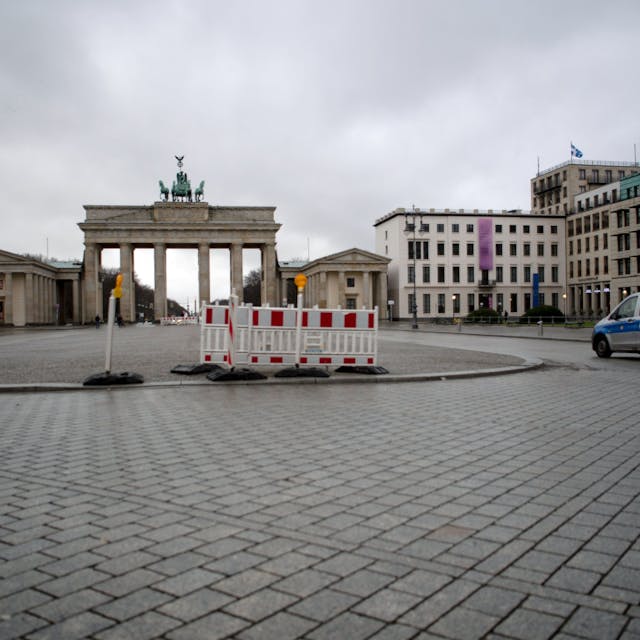 ARCHIV - 06.01.2021, Berlin: Ein Polizeifahrzeug fährt einen Tag nach dem Bund-Länder-Beschluss über eine Verlängerung des Lockdown über den fast menschenleeren Platz vor dem Brandenburger Tor.