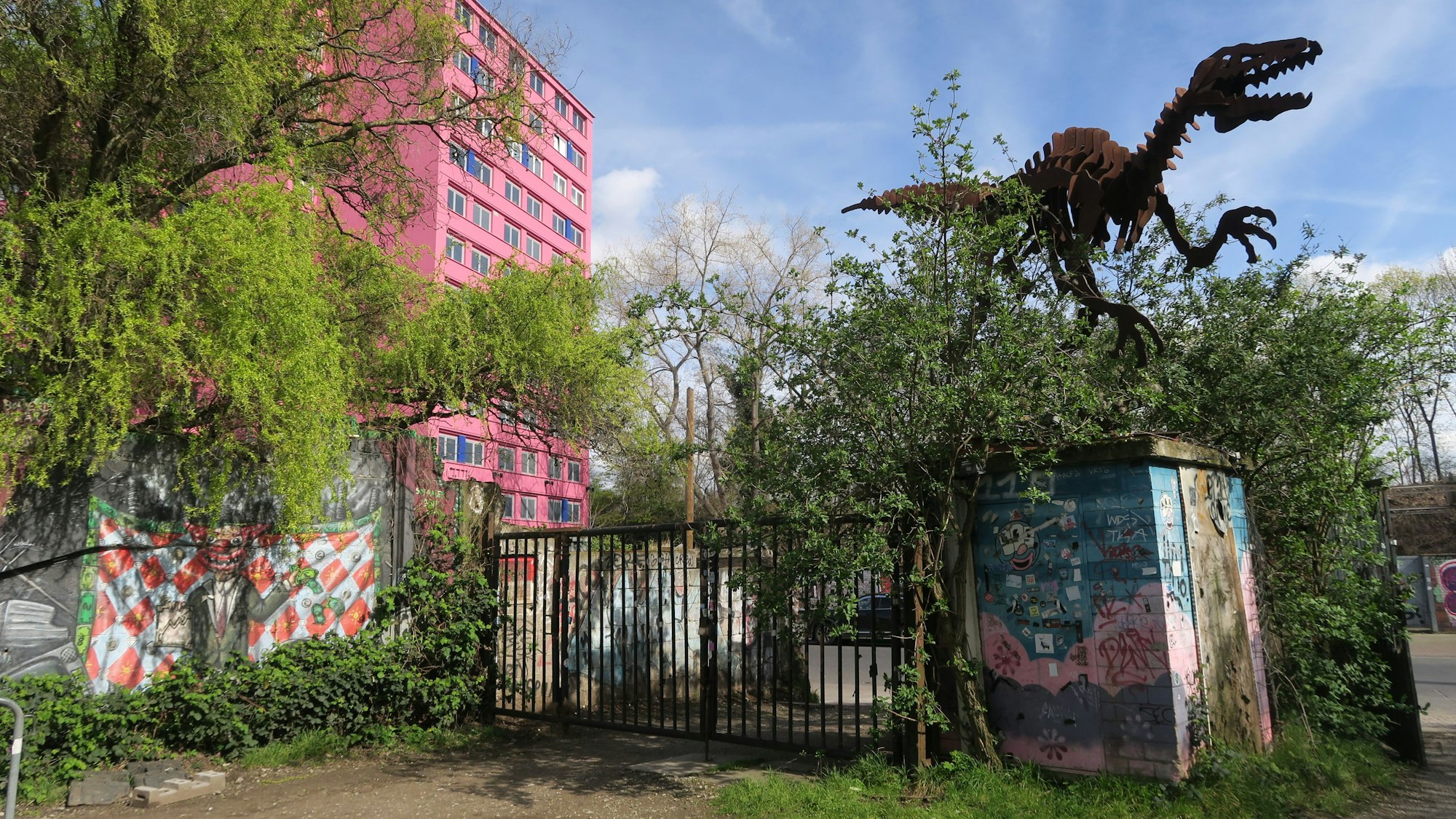 Das Odonien von außen, ein großer Dinosaurier aus Metall ragt über dem Eingang, im Hintergrund sieht man das Bordell „Pascha“