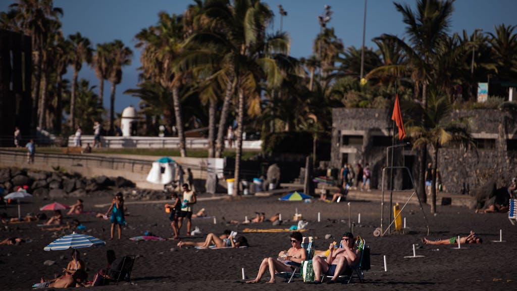 Touristinnen und Touristen sonnen sich am Playa Jardin in Santa Cruz in Teneriffa.