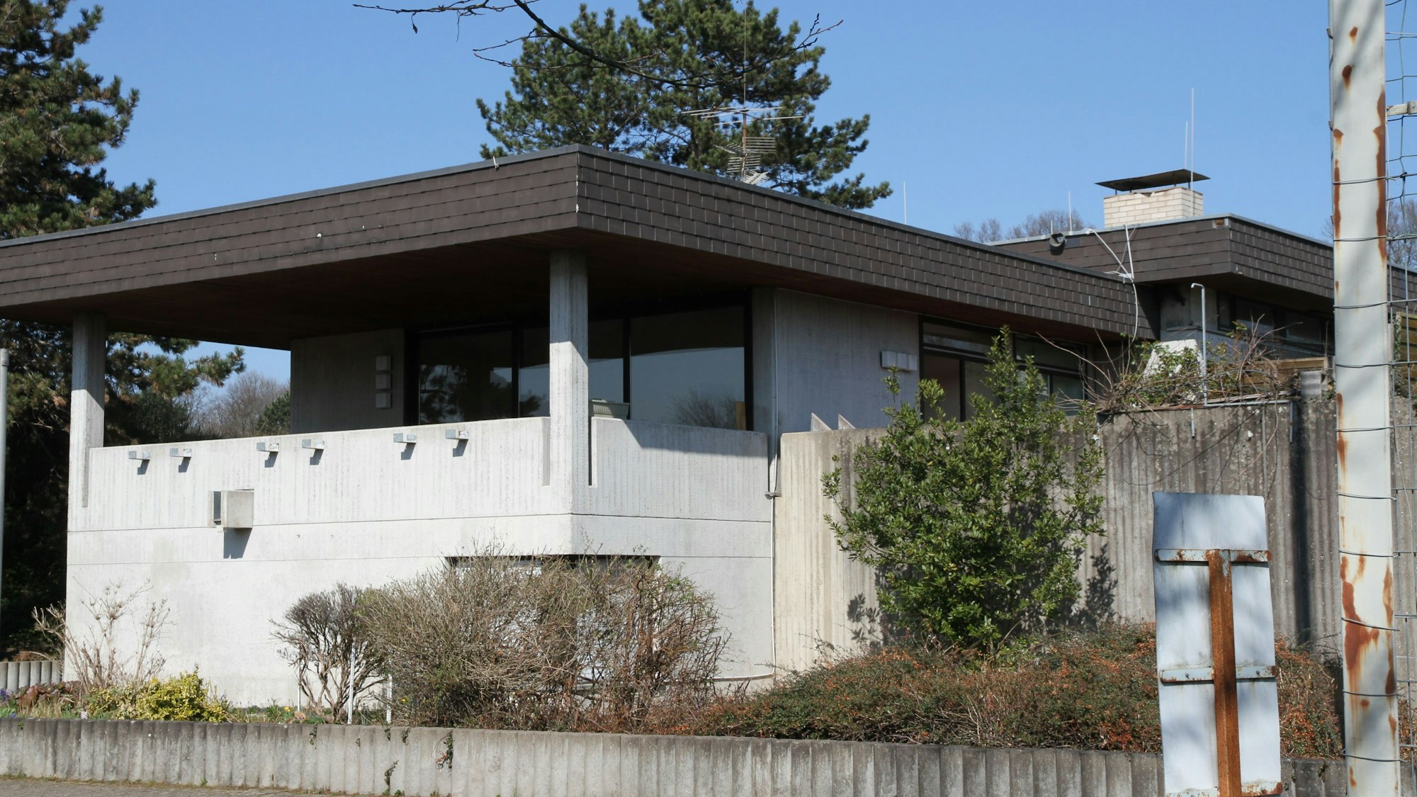 Ein Betonbau mit Balkon und dunklem Flachdach