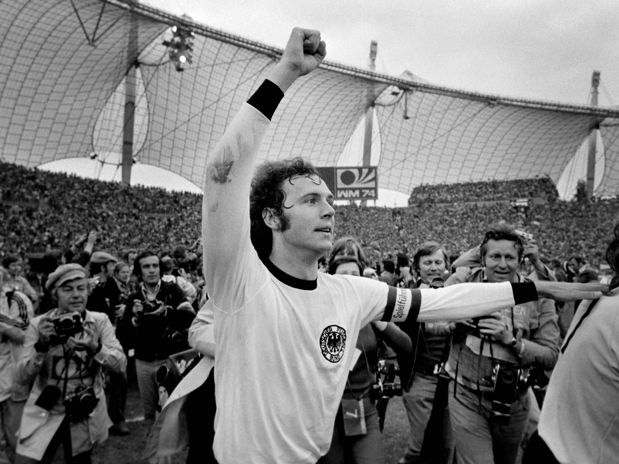 Franz Beckenbauer jubelt umzingelnd von Fotografen über den WM-Titel 1974.