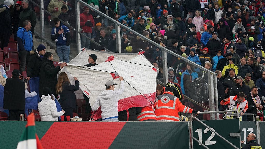 Sanitäter behandeln hinter einem Sichtschutz verletzte Personen auf der Tribüne der WWK Arena in Augsburg.