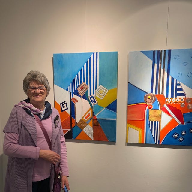 Eine Frau steht neben zwei farbigen Kunstwerken.