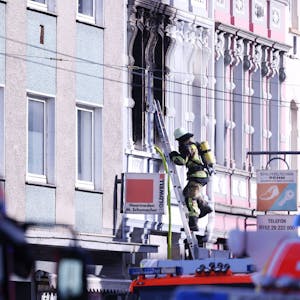 ARCHIV - 25.03.2024, Nordrhein-Westfalen, Solingen: Ein Feuerwehrmann klettert an einem Haus, in dem es gebrannt hat, auf einer Leiter.