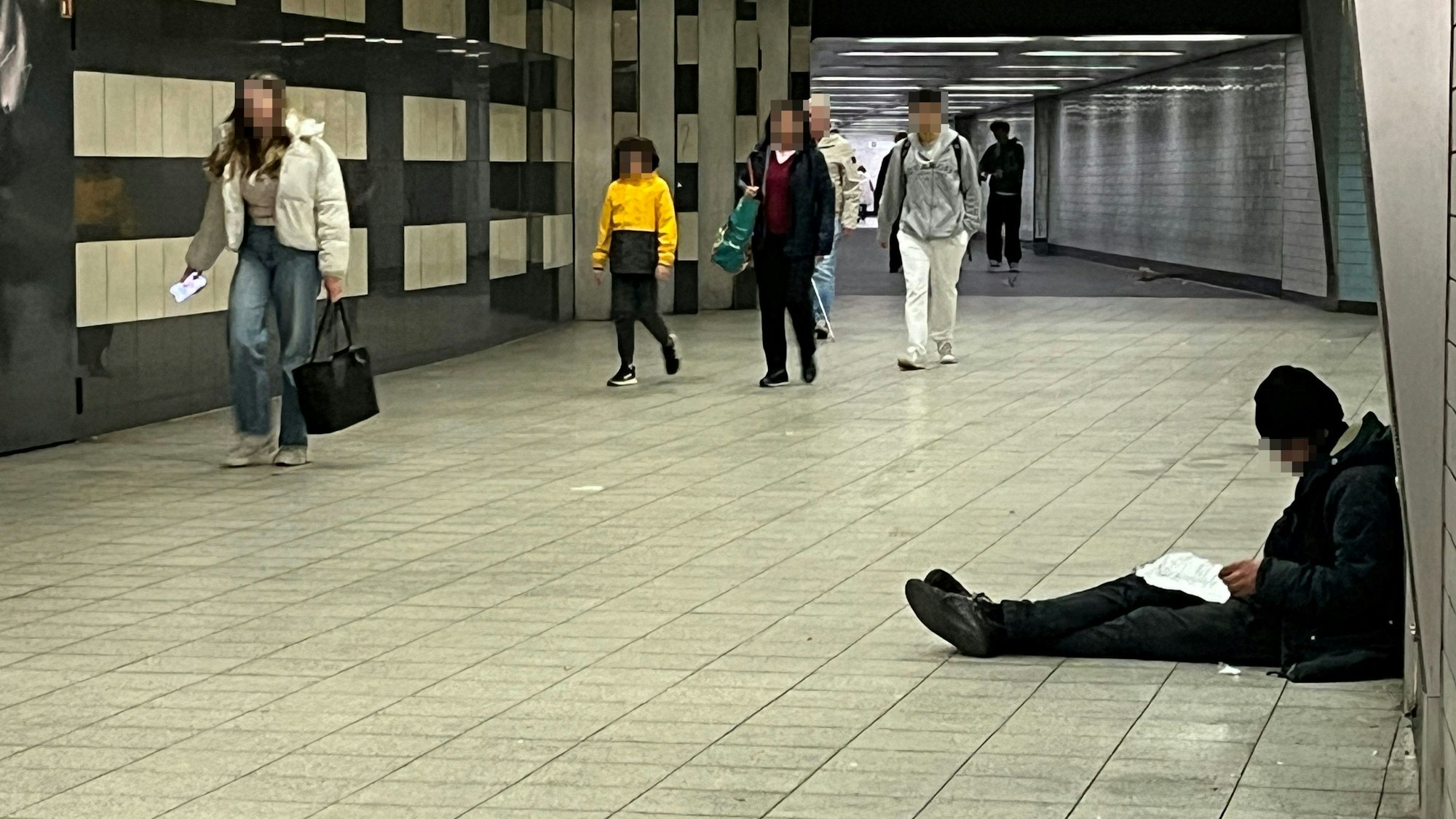 Drogenabhängiger sitzt auf dem Boden am Appellhofplatz und bereitet seinen nächsten Schuss vor, während Passanten vorbei gehen.