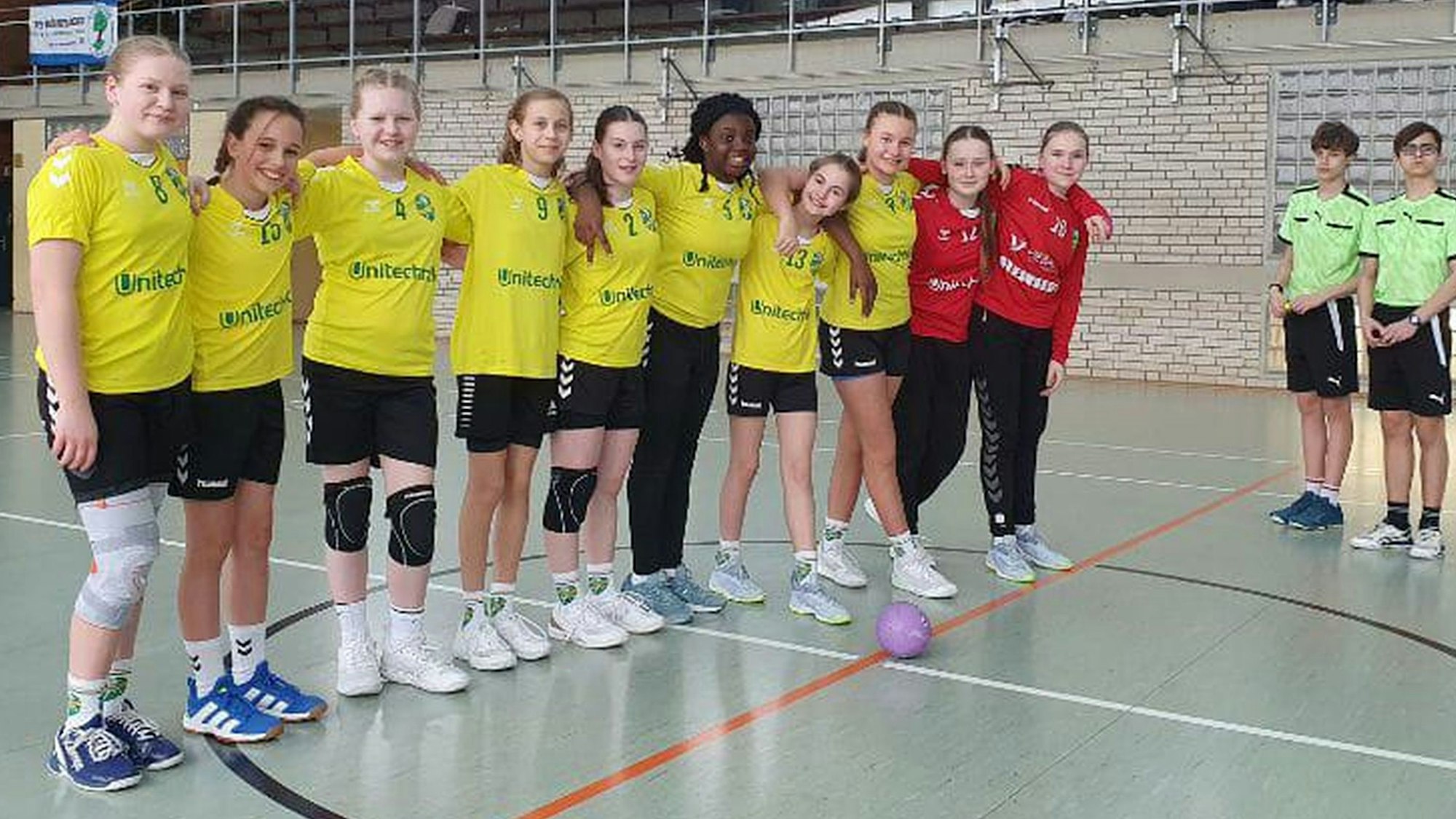 Mit den Armen über den Schultern stehen die D-Jugend-Handballerinnen des HC Gelpe/Strombach am Anwurfkreis.