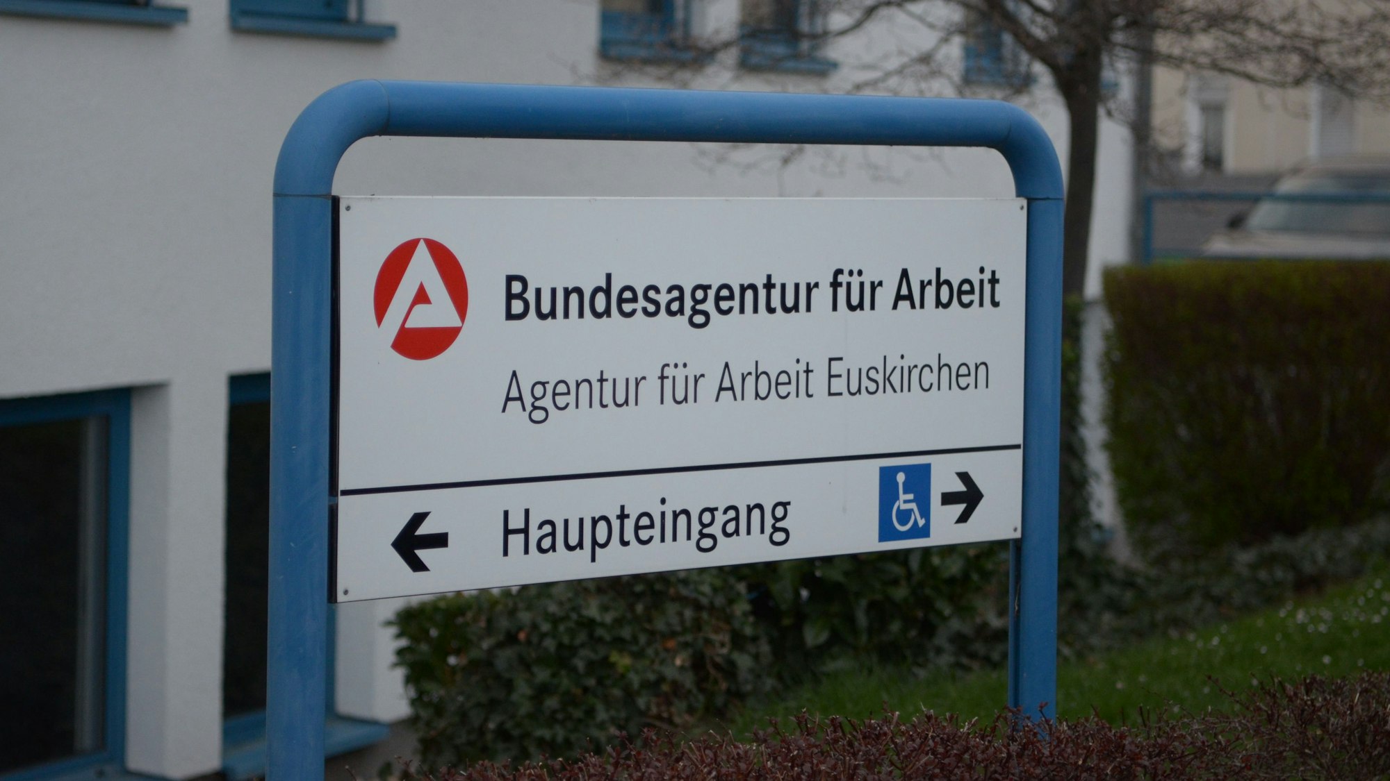 Ein Schild in einem blauen Rahmen weist den Weg zum Gebäude der Bundesagentur für Arbeit an der Thoméstraße in Euskirchen.