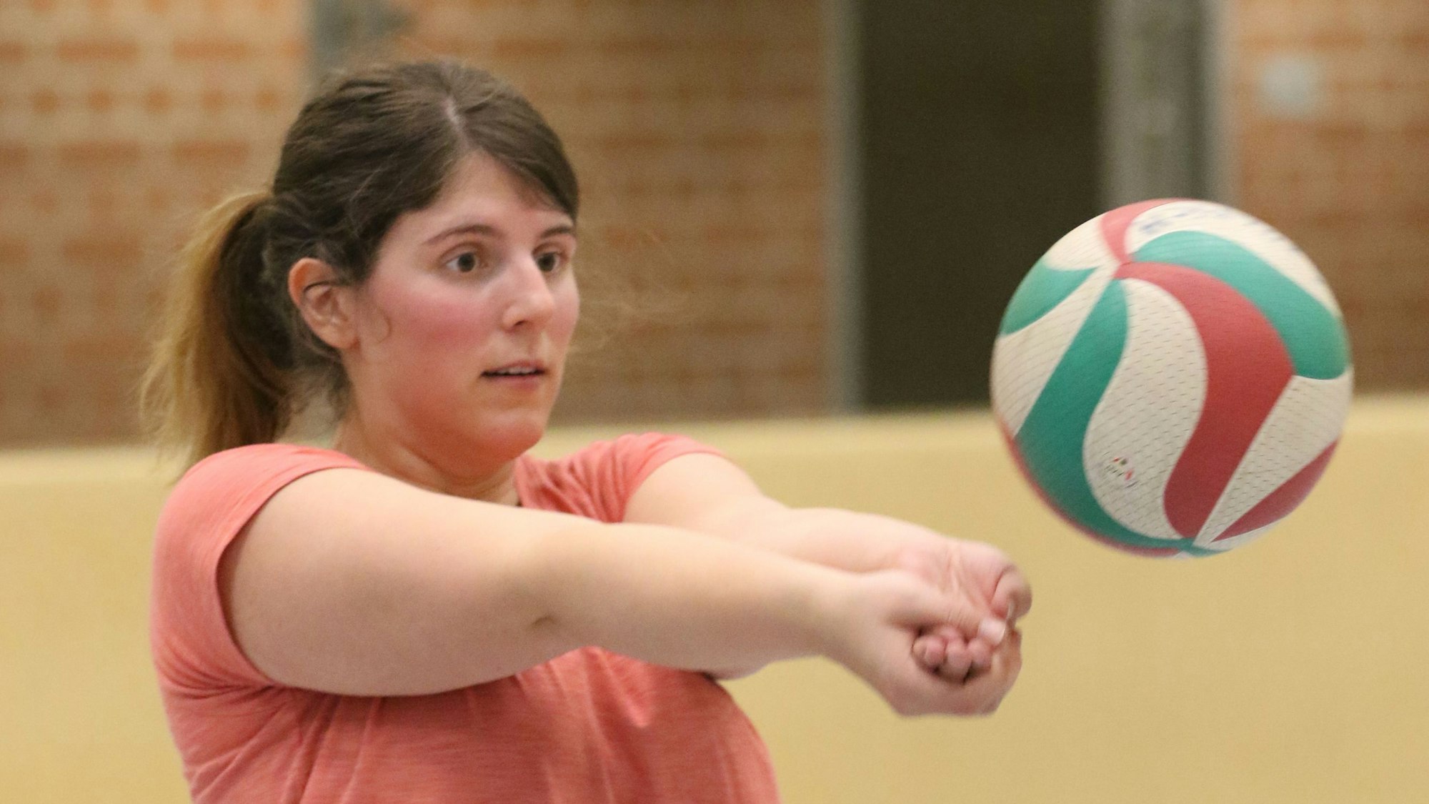 Julia Reuß fokussiert einen Volleyball und hat die Arme zum Baggern ausgestreckt, die Hände sind ineinander geschoben.