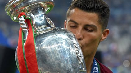 Auf dem Foto ist der portugiesische Nationalspieler Christiano Ronaldo zu sehen. Er küsst den EM-Pokal.