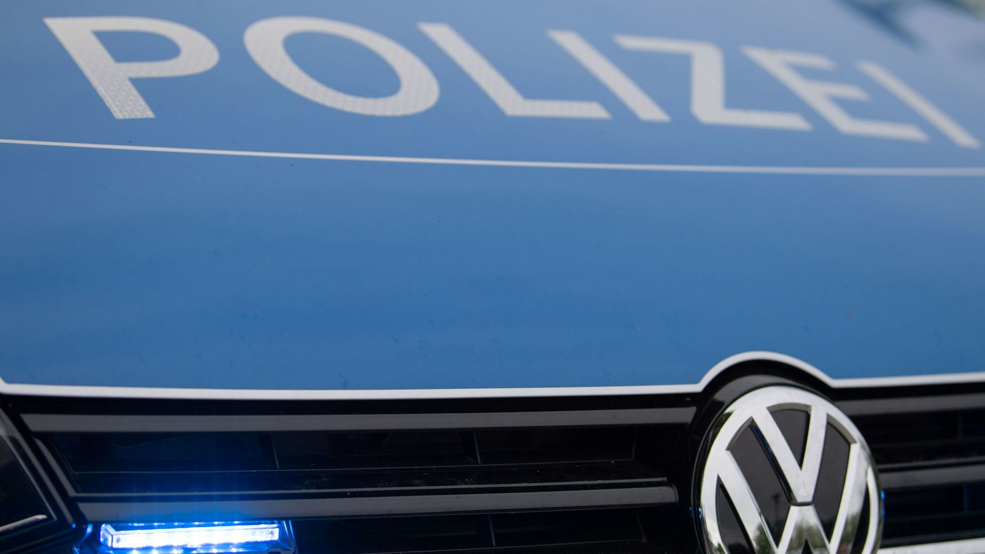 Ein Blaulicht leuchtet im Kühlergrill eines Polizeiautos.