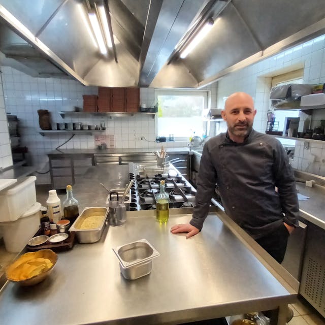 Mann in Kochjacke in einer Restaurantküche