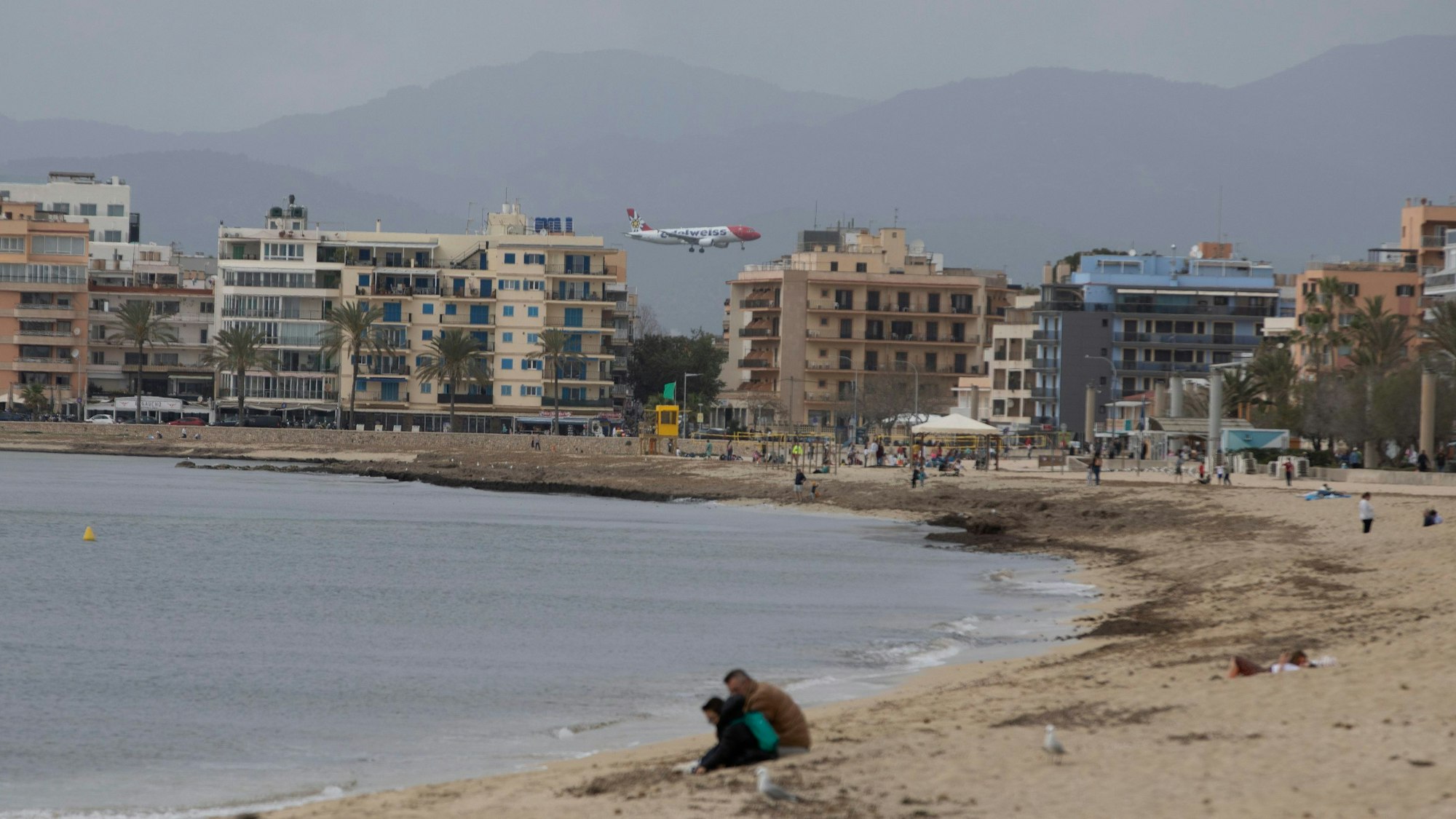 24.03.2024, Spanien, Palma: Ein Flugzeug kommt an einem bewölkten Tag zu Beginn der Osterferien auf Mallorca an, vom Strand von Arenal aus gesehen.