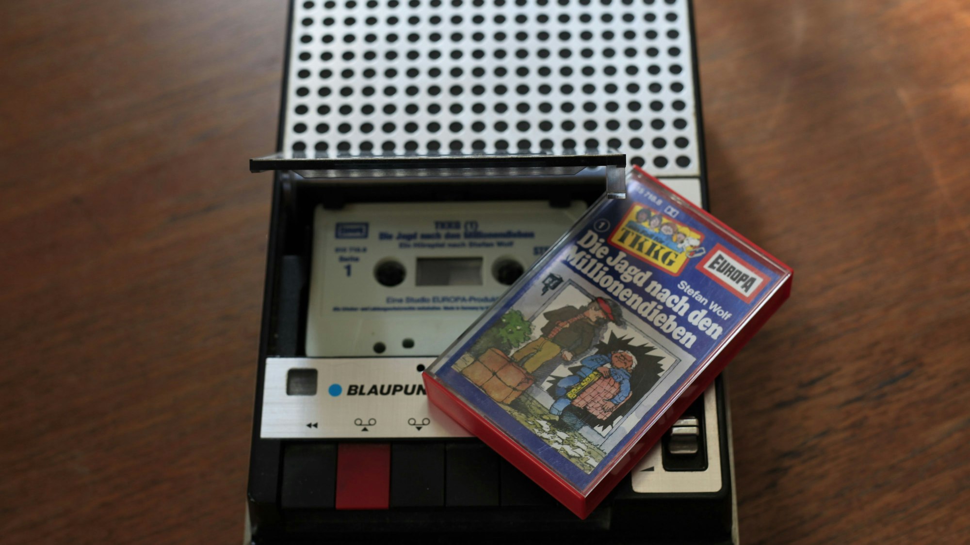 Eine Hörspielkassette aus der TKKG-Reihe liegt auf einem alten Kassetten-Rekorder.