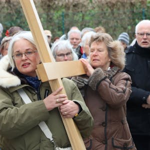Das Bild zeigt mehrere Christen, die ein Holzkreuz tragen.