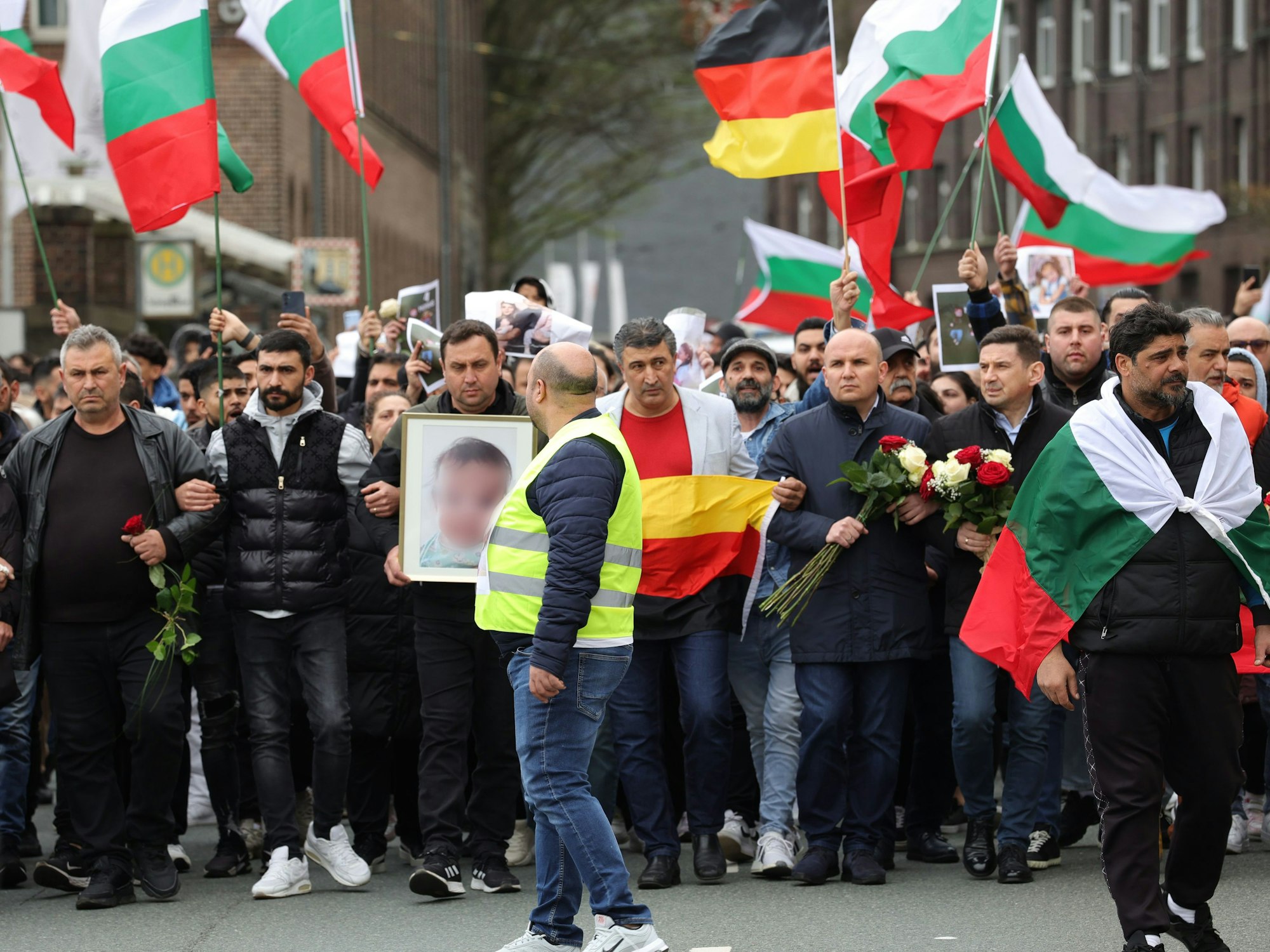 Mit bulgarischen und deutschen Flaggen zogen Teilnehmende am Samstag (30. März 2024) von der Innnenstadt zu dem ausgebrannten Haus, in dem eine aus Bulgarien stammende Familie ums Leben kam.