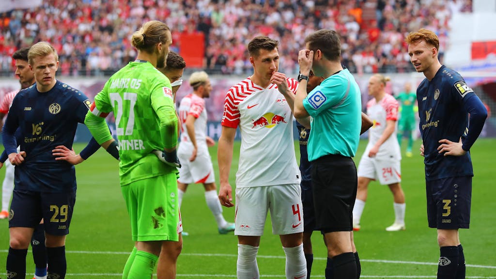 Schiedsrichter Frank Willenborg diskutiert beim Spiel zwischen RB Leipzig und Mainz 05 mit Spielern beider Teams.