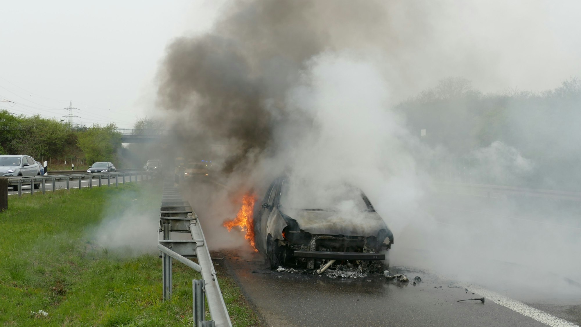 Ein brennendes Auto steht auf der Autobahn.