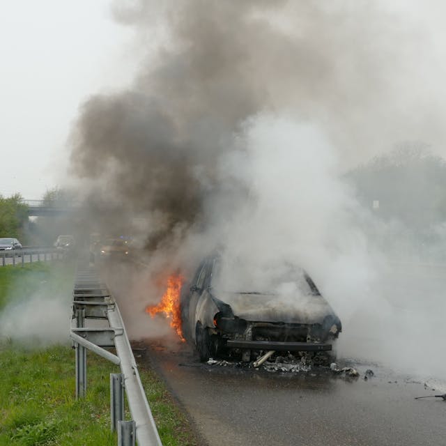 Ein brennendes Auto steht auf der Autobahn.