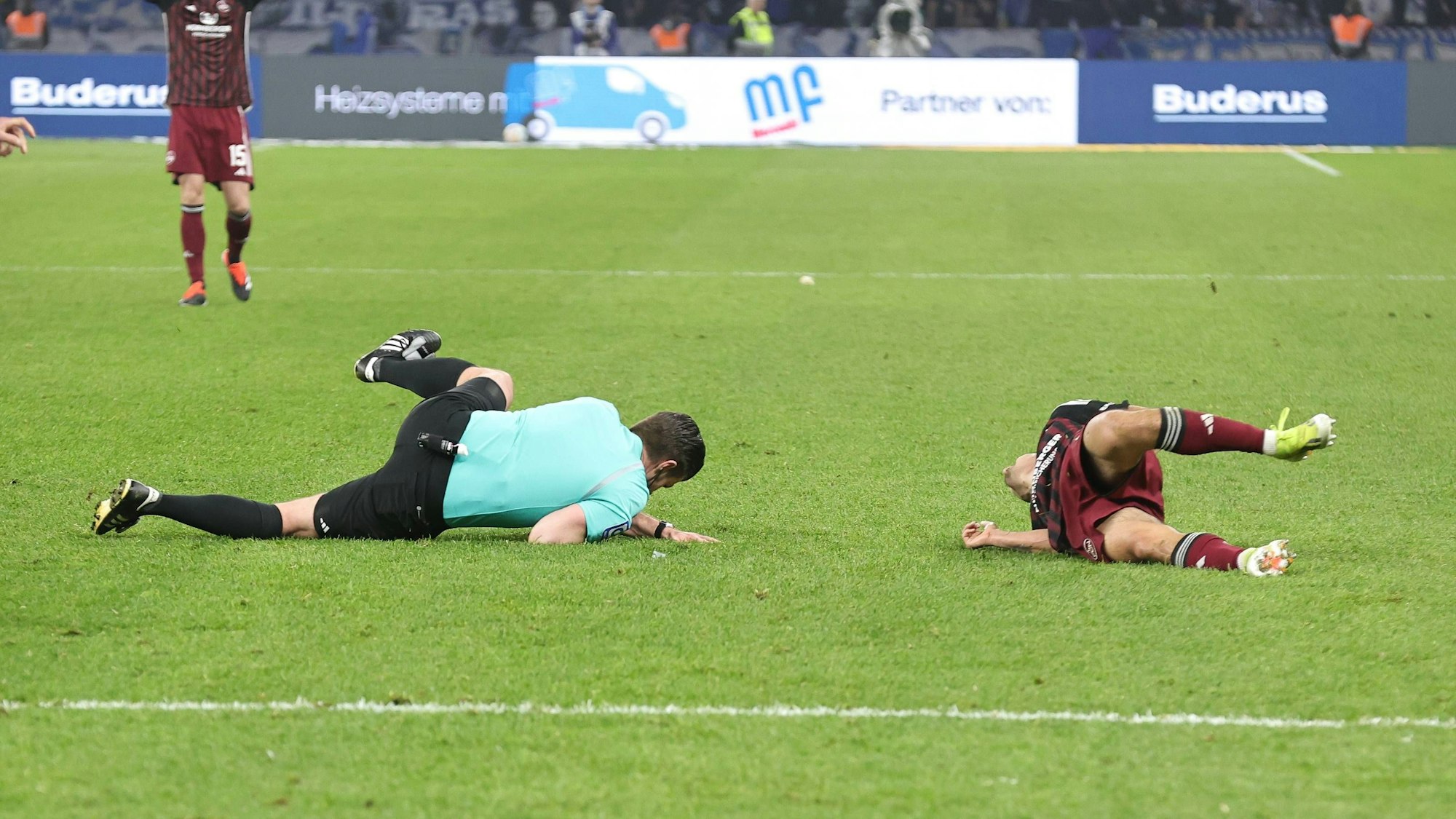 Nach dem heftigen Zusammenprall im Zweitliga-Topspiel in Berlin liegen Schiedsrichter Alexander Sather und Jens Castrop vom 1. FC Nürnberg am Boden.