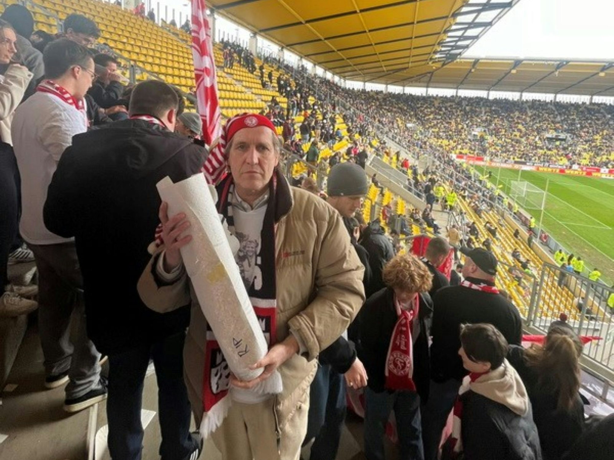Cornel Wachter steht auf der Zuschauertribüne im Fußballstadion und hält das zusammengerollte Banner in Händen.