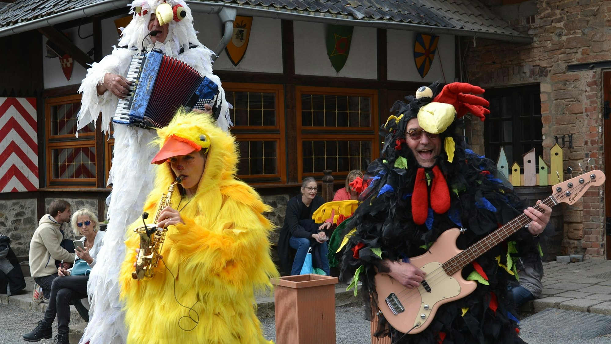 Drei verkleidete Musiker mit Akkordeon, Saxofon und Gitarre spielen im Innenbereich der Burg.