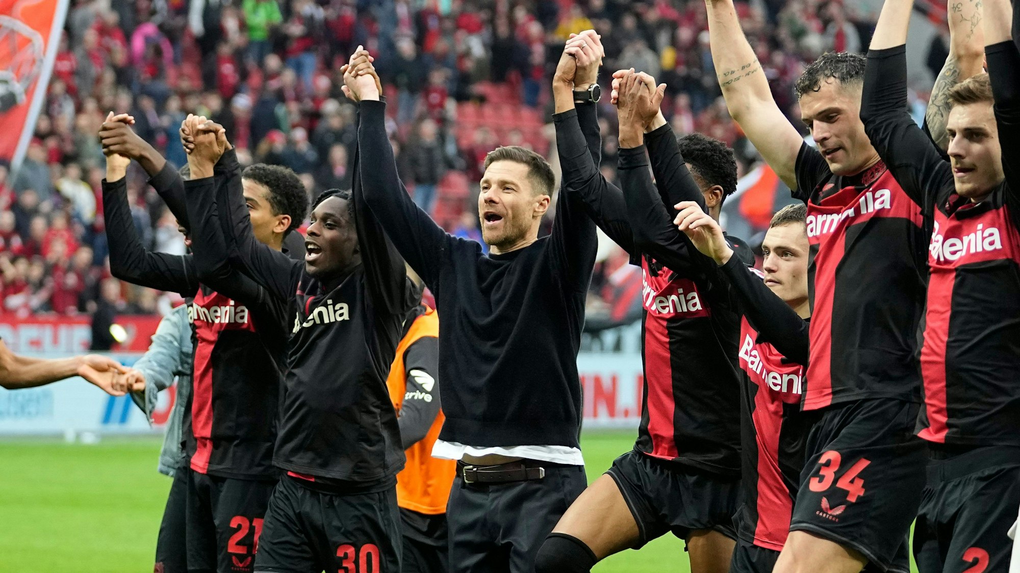 Leverkusen's head coach Xabi Alonso, center, celebrates with his team in front of supporters after winning the German Bundesliga soccer match between Bayer Leverkusen and TSG Hoffenheim at the BayArena in Leverkusen, Germany, Saturday, March 30, 2024. (AP Photo/Martin Meissner)