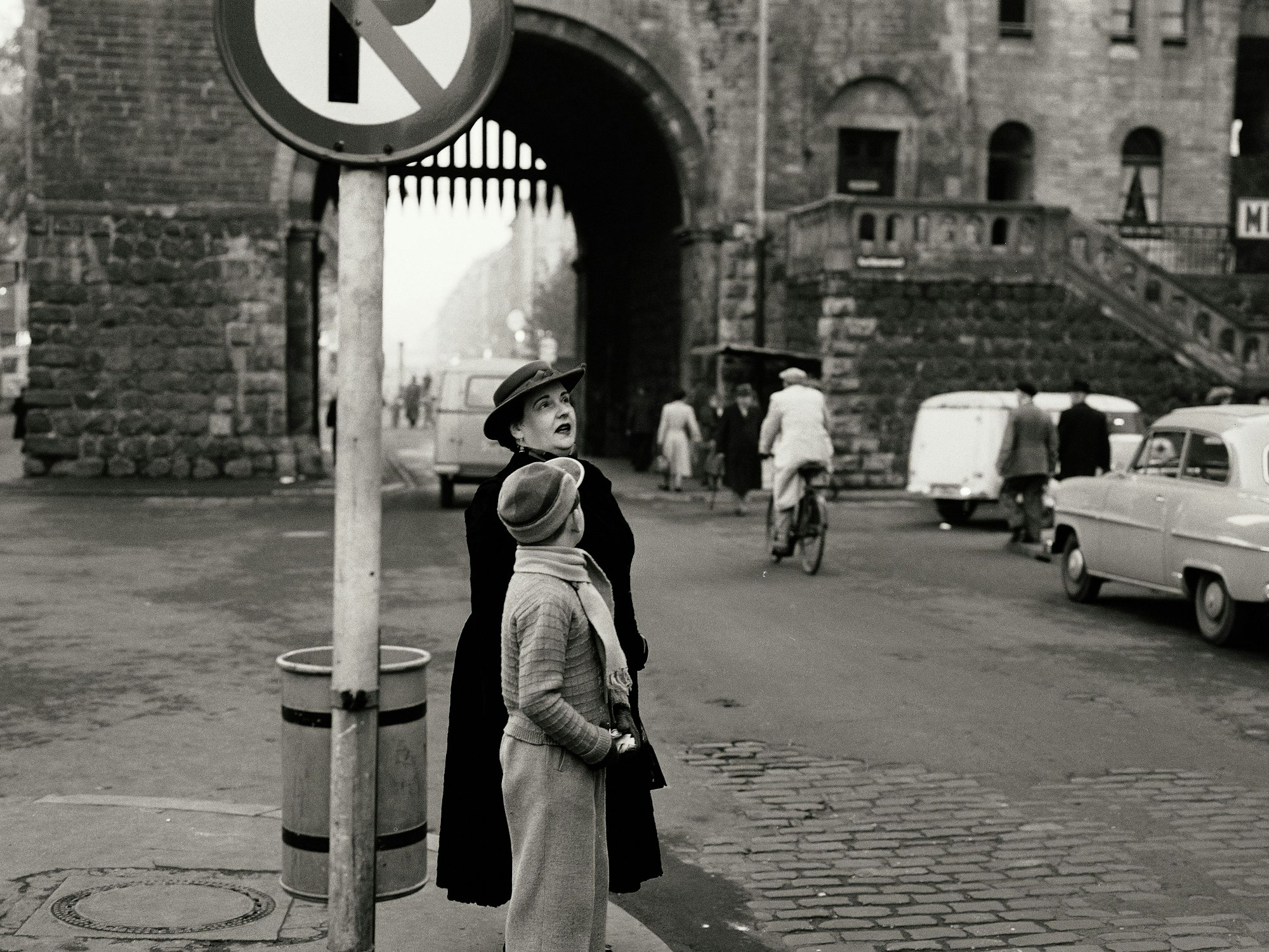 Mit Hut und Mantel: Eine Frau wartet am Straßenrand, gegenüber steht der Opel von Josef Niedecken.