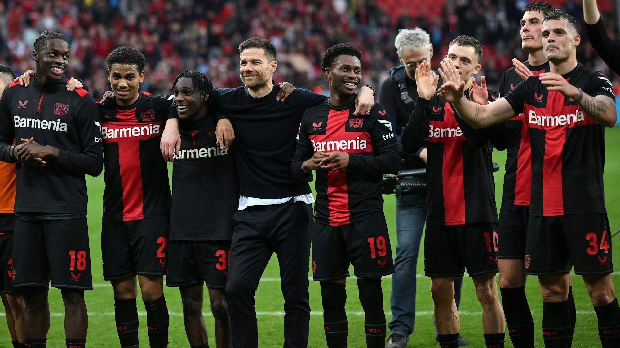 Xabi Alonso feiert nach dem Sieg von Bayer Leverkusen gegen die TSG Hoffenheim mit seinen Spielern Noah Mbamba, Amine Adli, Jeremie Frimpong, Nathan Tella, Florian Wirtz, Patrik Schick und Granit Xhaka.