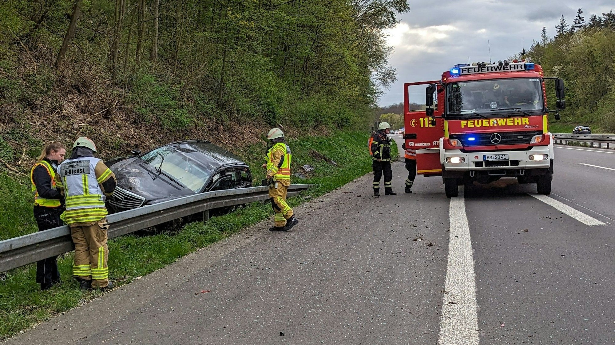 Zwei Personen haben sich bei einem Autounfall auf der A553 in Brühl verletzt. Feuerwehrleute sind an der Unfallaufnahmestelle zu sehen.