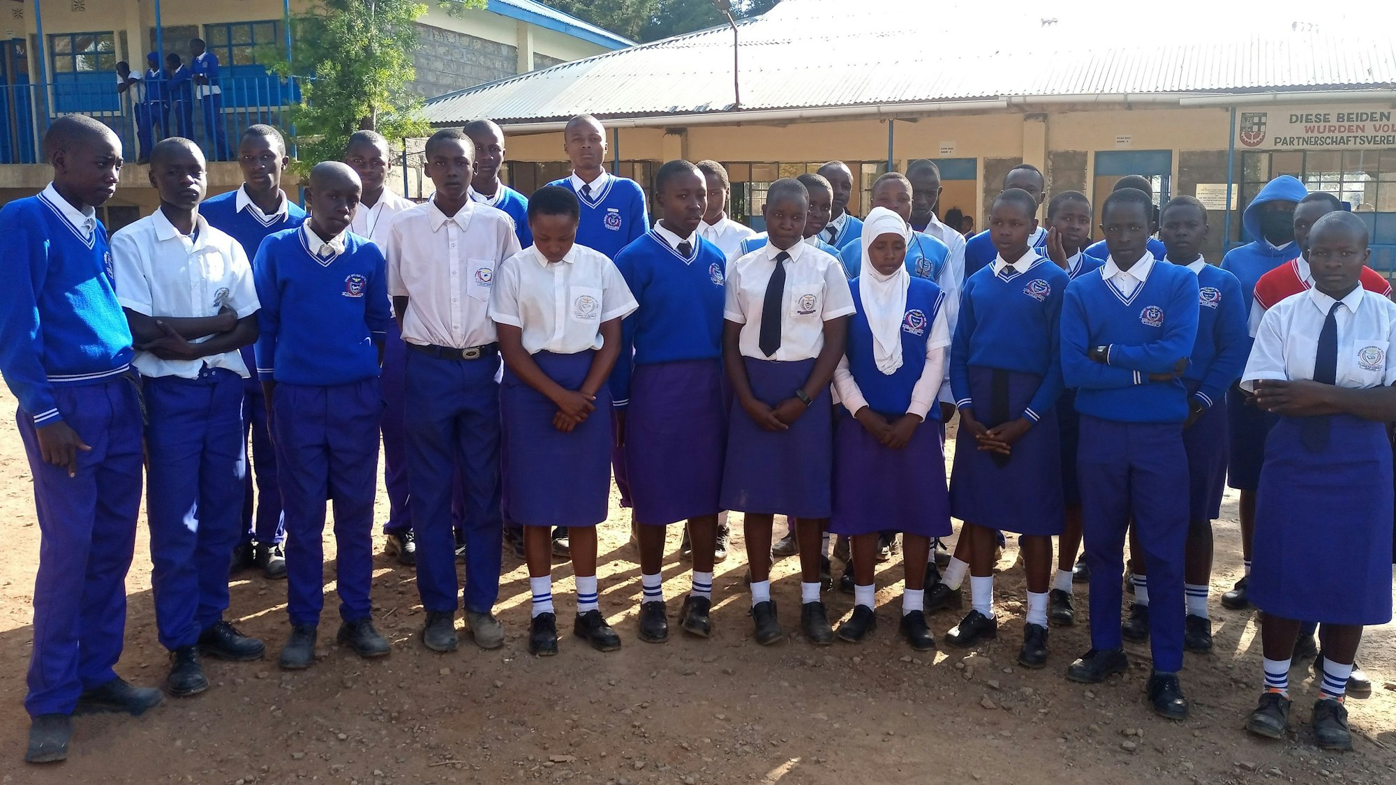 Das Foto zeigt eine Gruppe von Schülerinnen und Schülern in Schuluniform vor der Kabarnet-Hürth-Schule in der Partnerstadt in Kenia.