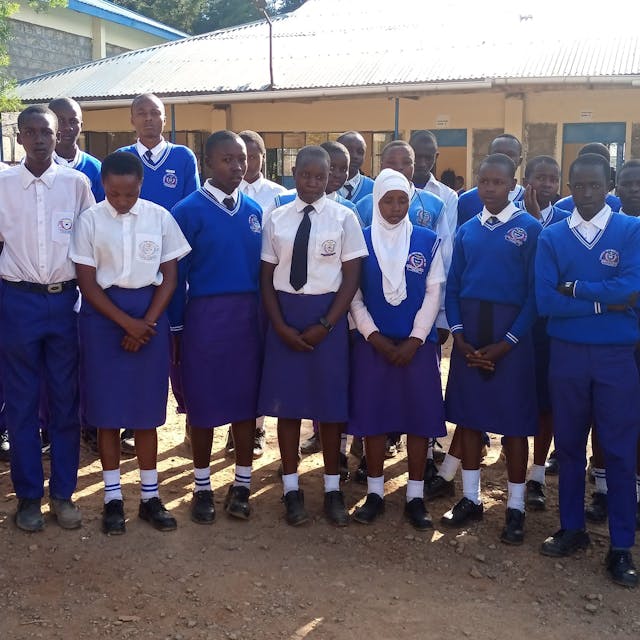 Das Foto zeigt eine Gruppe von Schülerinnen und Schülern in Schuluniform vor der Kabarnet-Hürth-Schule in der Partnerstadt in Kenia.