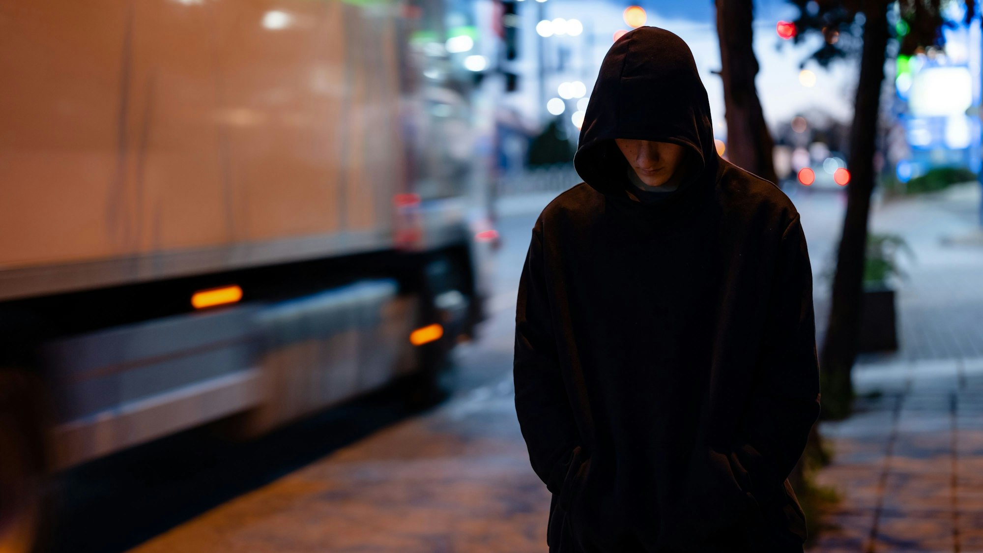 Faceless man with a black hoodie in the night city