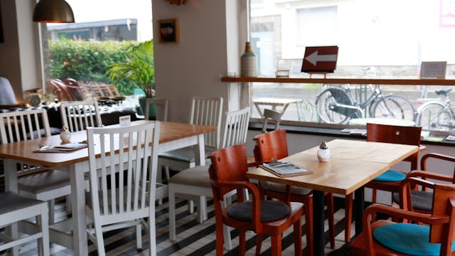 Das Café Bo in Zollstock von innen, zwei Holztische mit Holzstühlen und große Fenster