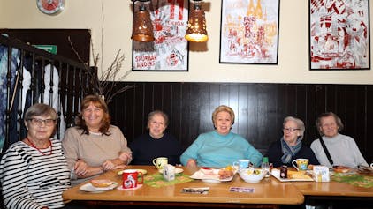 Sechs Seniorinnen, die an einem Tisch mit Frühstücksgedeck in einer Kölner Kneipe sitzen