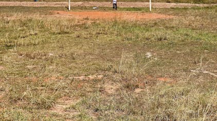 Ein Kind steht vor den Stangen eines Rugby-Tors auf einem Sportplatz in Südafrika. Im Hintergrund sind die Häuser einer Township zu sehen.