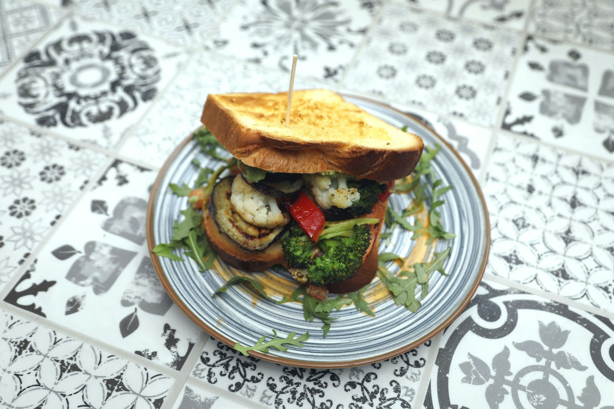 Auf einem Teller liegt ein üppig belegtes Sandwich mit Gemüse