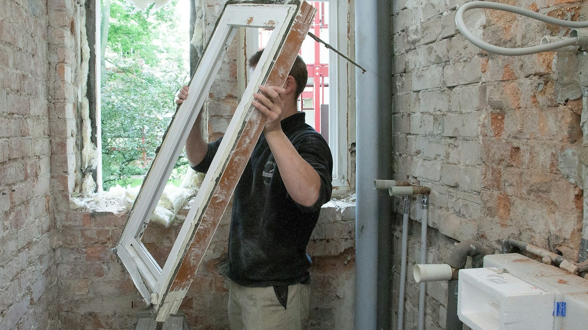 Ein Mann baut ein Fenster aus einem alten Haus aus.