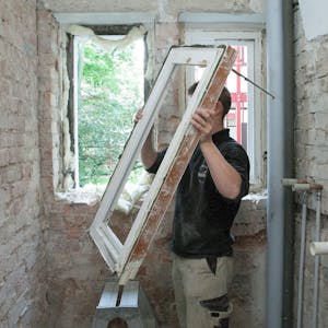 Ein Mann baut ein Fenster aus einem alten Haus aus.&nbsp;