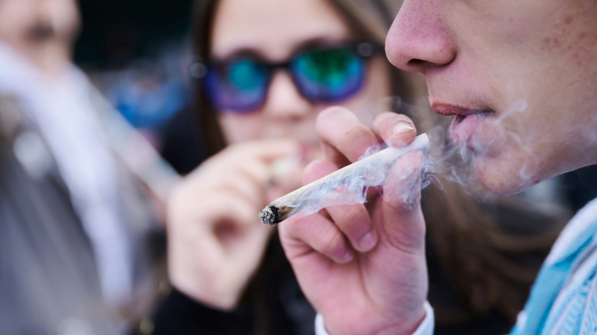 Zwei Menschen rauchen einen Joint bei einer Demonstration in Berlin.