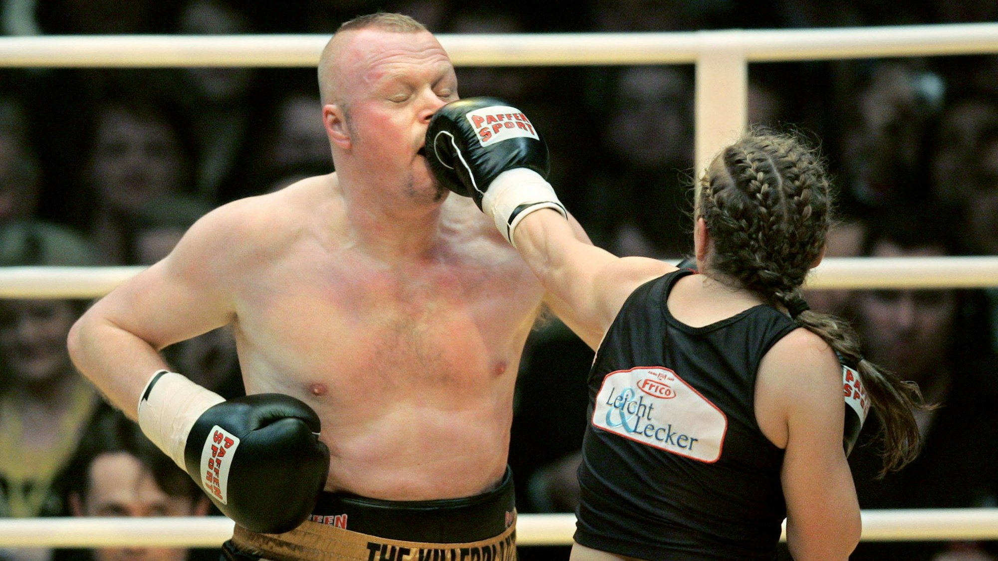 Actionbild aus dem Boxkampf zwischen Stefan Raab und Regina Halmich im Jahr 2007. Im Bild trifft Halmich Raab gerade mit einem Schlag am Kopf.
