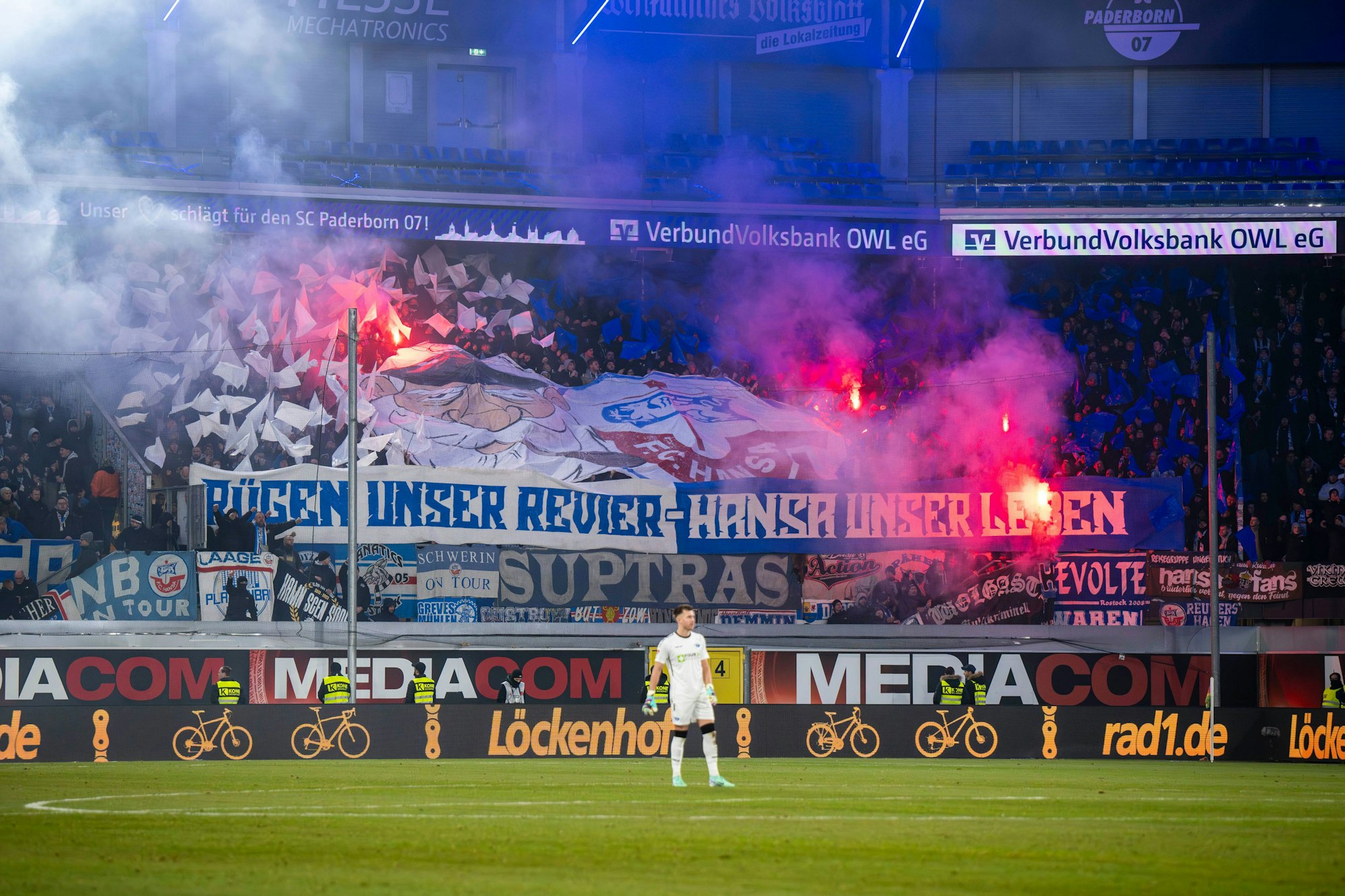 Die Rostocker Fans halten Banner mit der Aufschrift „Rügen unser Revier - Hansa unser Leben“ und zünden Pyrotechnik.